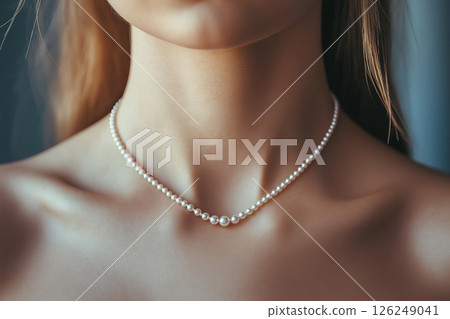 A detailed close-up captures a stylish pearl necklace gracefully resting on a woman's neckline, emphasizing elegance, sophistication, and timeless beauty under gentle lighting. 126249041