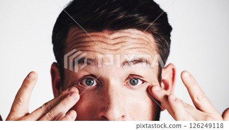 Man, studio and stress with eye irritation on white background with infection, glaucoma and concern. Contact lenses, portrait and person frown with reaction to allergy, vision loss or retina wellness 126249118