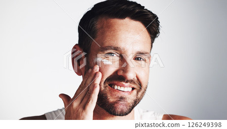 Apply, portrait and happy man with face cream for anti aging, skincare space or collagen. Smile, wrinkle treatment or male person on white background in studio for cosmetics, beauty or facial lotion 126249398