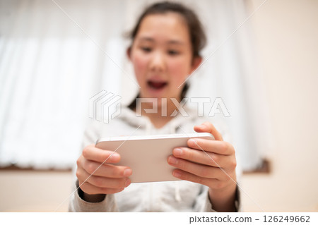 A girl watching a smartphone A girl watching a smartphone 126249662