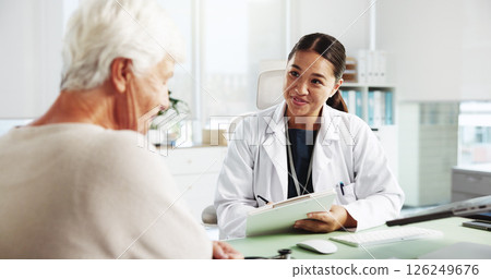 Senior woman, happy doctor and consultation with clipboard for healthcare report, symptoms or checkup. Medical professional, appointment and talking to patient for help or writing results in hospital Senior woman, happy doctor and consultation with clipboard for healthcare report, symptoms or checkup. Medical professional, appointment and talking to patient for help or writing results in hospital 126249676