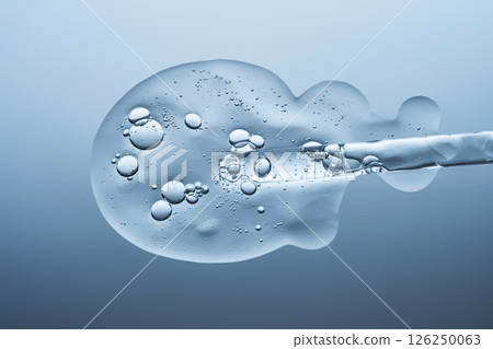 Transparent serum with bubbles and dropper dropper on a blue background. Transparent serum with bubbles and dropper dropper on a blue background. 126250063