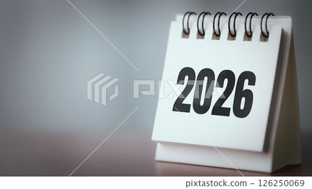 Desk Calendar Showing 2026 on Wooden Table with Blurred Background and Copy Space Desk Calendar Showing 2026 on Wooden Table with Blurred Background and Copy Space 126250069