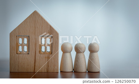 Wooden House Model and Figurines on a Table with Blurred Background 126250070