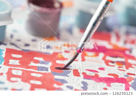 Close up of paintbrush on colorful paint by numbers canvas with blurred paint Close up of paintbrush on colorful paint by numbers canvas with blurred paint 126250123