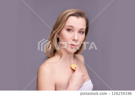Caucasian young female holding skincare product against chest with neutral Caucasian young female holding skincare product against chest with neutral 126250196