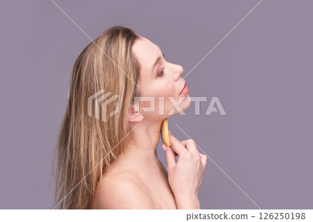 Young caucasian female using facial roller for skin care on neutral background 126250198