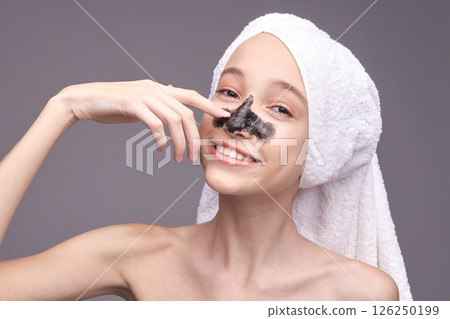 Young caucasian female skincare routine with facial mask and white towel on head Young caucasian female skincare routine with facial mask and white towel on head 126250199