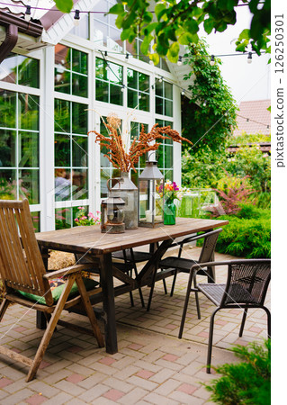 wooden table with lanterns and dried flowers. The yard in the house. wooden table with lanterns and dried flowers. The yard in the house. 126250301