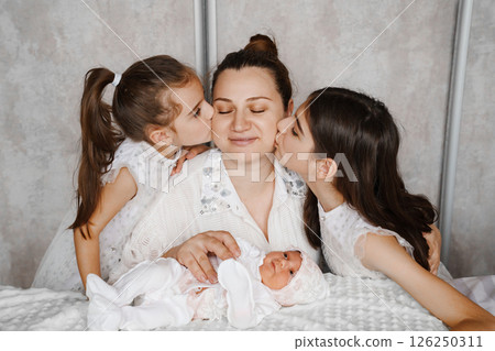 Happy mother with a newborn and older daughters. Happy mother with a newborn and older daughters. 126250311