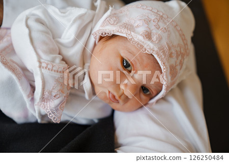 Newborn baby in a hat with pink lace in arms 126250484