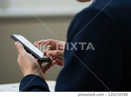 The hands of a student in uniform operating a smartphone (AI-generated image) The hands of a student in uniform operating a smartphone (AI-generated image) 126250506