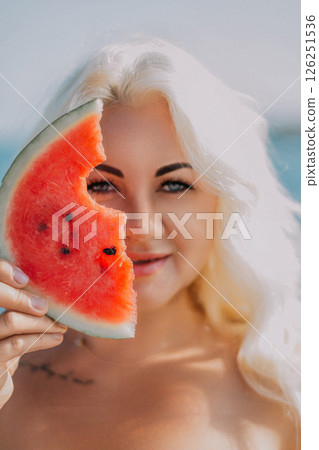 Watermelon Woman Summer Beach: Portrait of a blonde woman holding a watermelon slice near the ocean, enjoying summer. Watermelon Woman Summer Beach: Portrait of a blonde woman holding a watermelon slice near the ocean, enjoying summer. 126251536