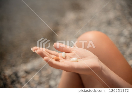 A person is holding a handful of nuts in their hand. The nuts are of different sizes and shapes, and they appear to be almonds. The person seems to be enjoying the nuts and is likely to eat them soon. 126251572