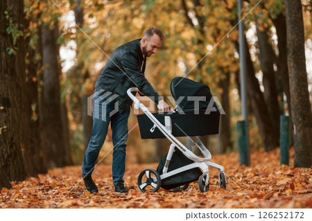 Man with pram is having a walk in the autumn park 126252172