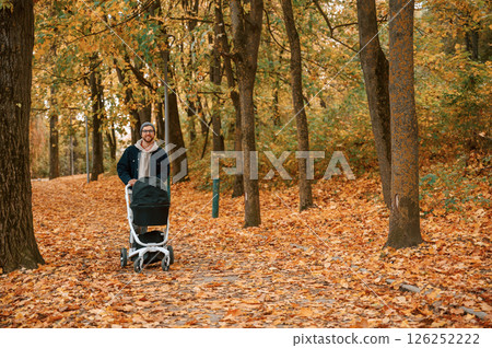 Enjoying the nature. Man with pram is having a walk in the autumn park 126252222