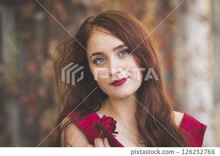 portrait of a young girl in a red dress against the background of autumn trees with a rose portrait of a young girl in a red dress against the background of autumn trees with a rose 126252768