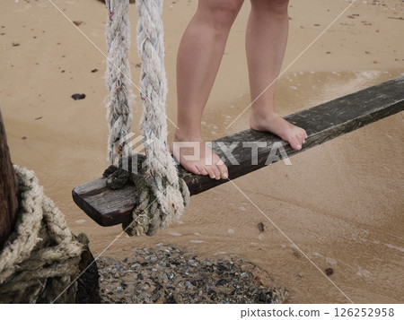 Engaging in the activity of balancing on a wooden beam positioned by the beautiful shoreline 126252958