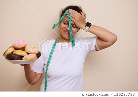 Woman Struggles With Healthy Choices, Holding Donuts and Measuring Tape Woman Struggles With Healthy Choices, Holding Donuts and Measuring Tape 126253788