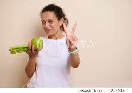 Cheerful Woman Holding Green Apple and Celery Promoting Healthy Eating 126253831