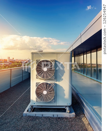 Rooftop air conditioning units at sunset overlooking a modern city skyline in warm evening light Generative AI 126254947