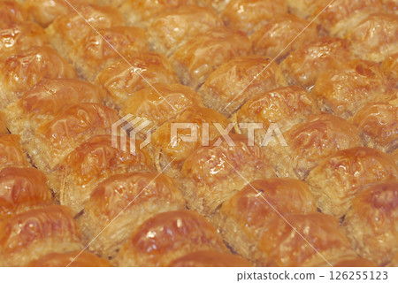 Freshly baked baklava prepared in a busy bakery kitchen 126255123