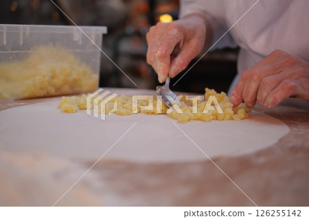 Baker preparing dough with diced fruit at a busy kitchen 126255142