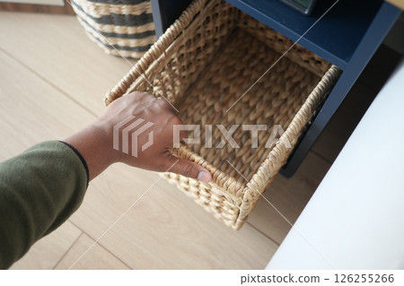 Hand reaching for a woven basket in a modern home 126255266