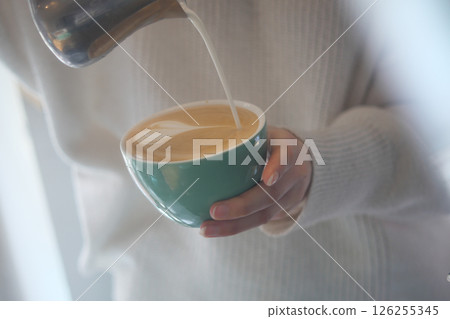 Pouring milk into a coffee cup at a cozy cafe in the morning 126255345