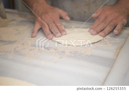 Baker prepares dough for fresh bread in a bakery 126255355