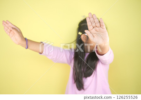 Girl poses playfully by a yellow backdrop 126255526