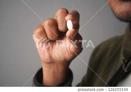 Person holds white pill in hand before consumption 126255539