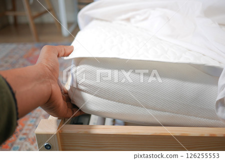 Mattress being adjusted in a cozy bedroom setting Mattress being adjusted in a cozy bedroom setting 126255553
