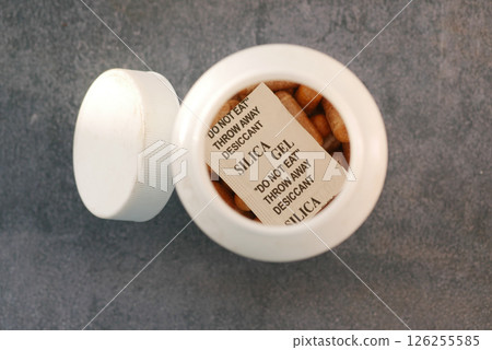 Silica gel container with warning label on a gray surface Silica gel container with warning label on a gray surface 126255585