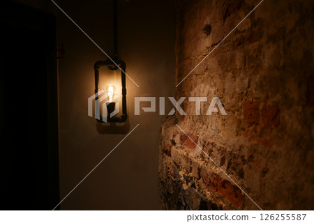 Rustic wall sconce illuminating vintage brick in dimly lit room Rustic wall sconce illuminating vintage brick in dimly lit room 126255587