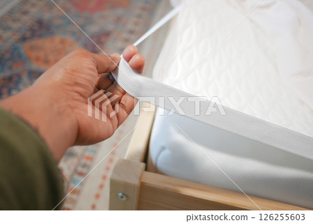 Adjusting the fitted sheet on a bed during home organization Adjusting the fitted sheet on a bed during home organization 126255603