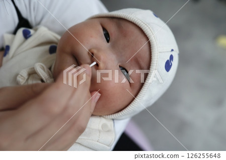 用棉花棒清潔 2 個月大的嬰兒的鼻孔 126255648