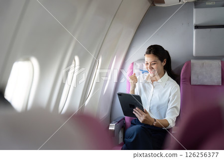 Business Travel. Happy woman celebrating on tablet during flight. 126256377