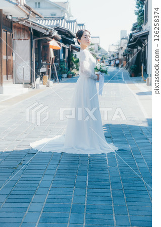 Portrait of a woman in a wedding dress standing in a traditional street 126258374