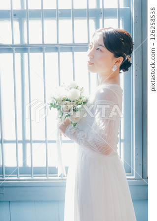 身穿白色洋裝的女子站在窗邊的剪影式肖像 126258538