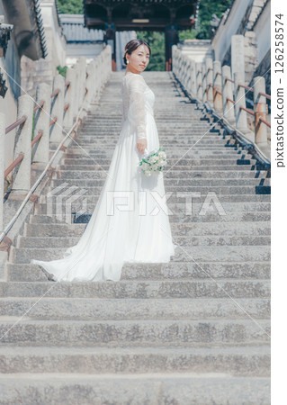 A woman in a wedding dress standing on stone steps 126258574