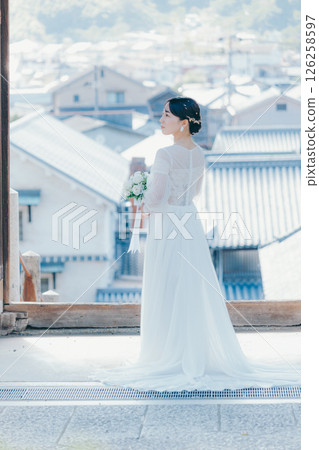 一位身著婚紗的女子從山上的神社俯瞰小鎮的畫像 一位身著婚紗的女子從山上的神社俯瞰小鎮的畫像 126258597