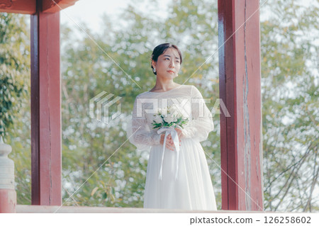 一位身著婚紗的女子從山上的神社俯瞰小鎮的畫像 126258602