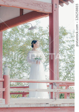 一位身著婚紗的女子從山上的神社俯瞰小鎮的畫像 126258603