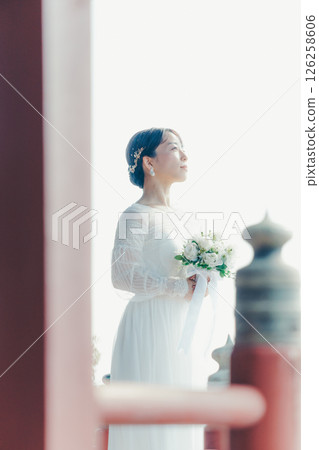 一位身著婚紗的女子從山上的神社俯瞰小鎮的畫像 126258606