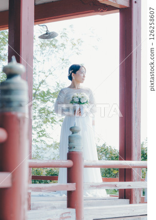 一位身著婚紗的女子從山上的神社俯瞰小鎮的畫像 一位身著婚紗的女子從山上的神社俯瞰小鎮的畫像 126258607