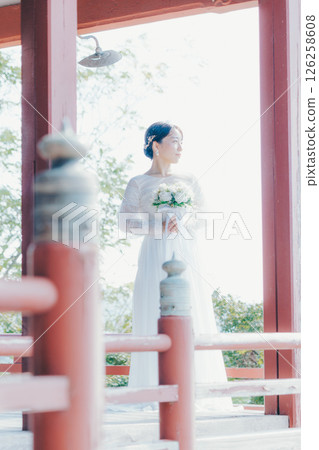 Portrait of a woman in a wedding dress looking out over the town from a shrine on a hill Portrait of a woman in a wedding dress looking out over the town from a shrine on a hill 126258608