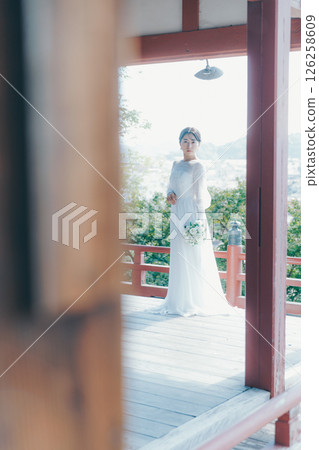 一位身著婚紗的女子從山上的神社俯瞰小鎮的畫像 一位身著婚紗的女子從山上的神社俯瞰小鎮的畫像 126258609