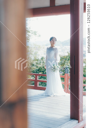 一位身著婚紗的女子從山上的神社俯瞰小鎮的畫像 一位身著婚紗的女子從山上的神社俯瞰小鎮的畫像 126258610