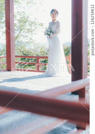 一位身著婚紗的女子從山上的神社俯瞰小鎮的畫像 一位身著婚紗的女子從山上的神社俯瞰小鎮的畫像 126258612